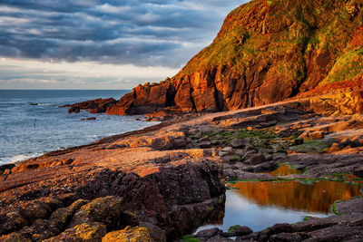 Scenic view of rock formations by sea against sky