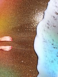 Low section of woman standing on sand