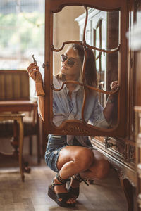 Young woman seen through cabinet glass door at home