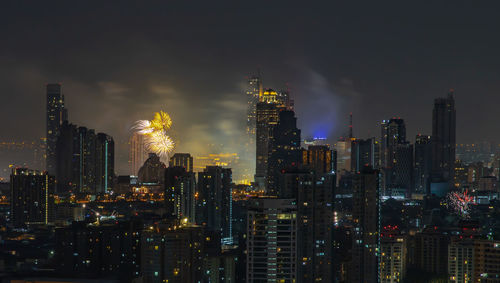 Illuminated buildings in city against sky at night