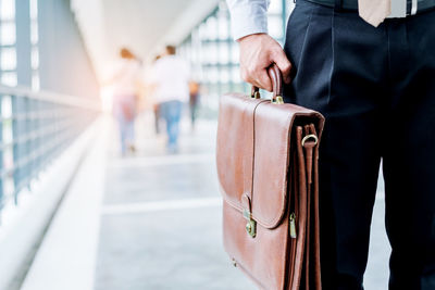 Midsection of businessman holding bag while standing on covered bridge