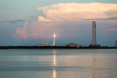 Rocket taking off by sea against sky