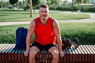 Portrait of young man sitting on bench in park