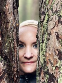 Portrait of smiling woman against tree trunk