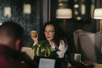 Young woman using phone while sitting on table