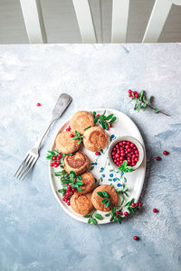 Breakfast set. russian cheese cakes on a craft ceramic plate with lingonberry over a blue background