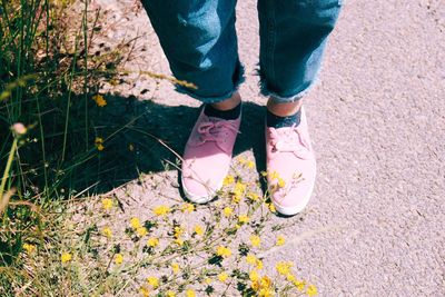 Low section of woman standing on flowering plants