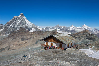 Built structure on snowcapped mountain against clear blue sky