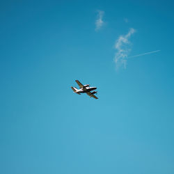 Low angle view of airplane flying against blue sky