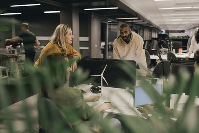 Male and female coworkers discussing at office desk