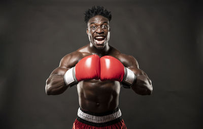 Portrait of shirtless boxer standing against black background