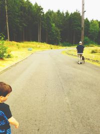 Rear view of boy riding motorcycle on road