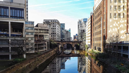 Canal in city against sky