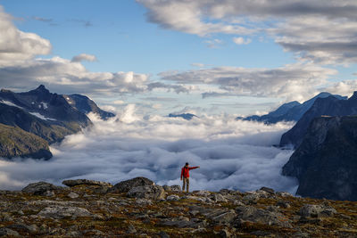 Rear view of man standing on rock against sky