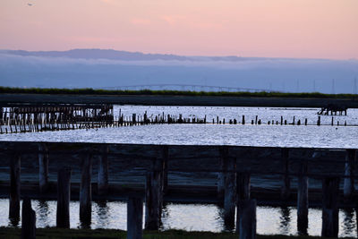 Pier on lake against sky during sunset