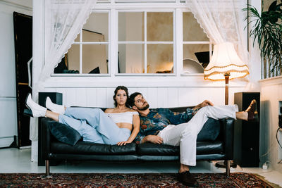 Young stylish couple sitting on sofa indoors