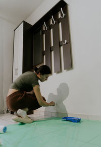 A young girl paints a wall with a brush.