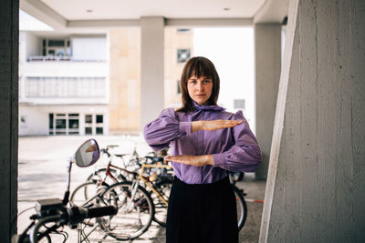 Portrait of woman with bicycle standing against wall