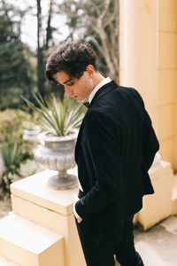 Side view of young man standing against wall