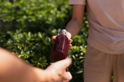 Midsection of man holding bottle