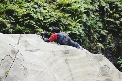 Man sitting on rock against trees