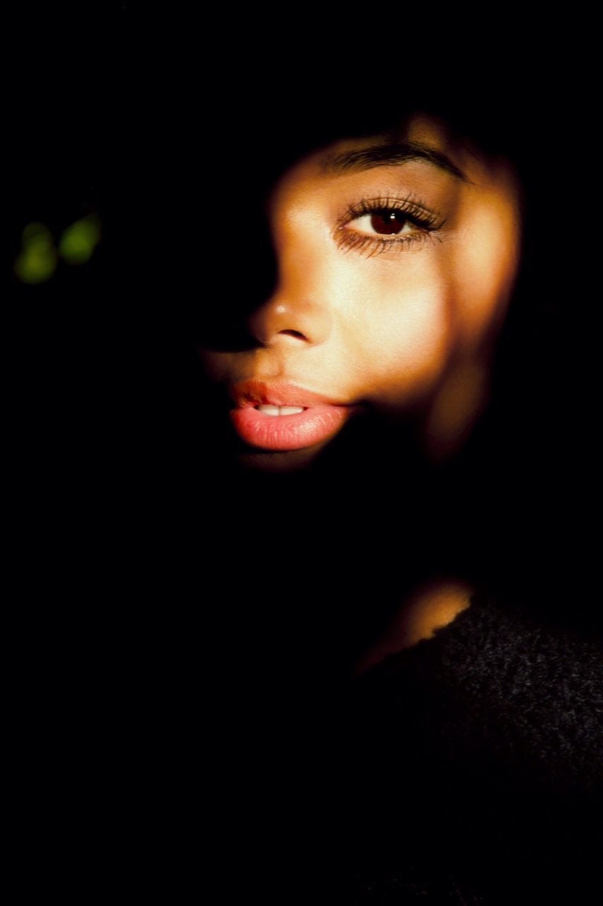 black background, portrait, looking at camera, young adult, lifestyles, night, person, front view, studio shot, headshot, indoors, leisure activity, dark, young women, close-up, serious, contemplation