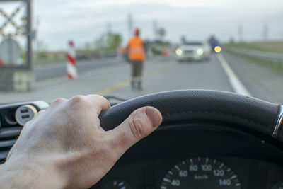 Driver hand is on the steering wheel, which stands and passes oncoming cars
