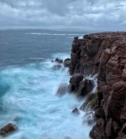 Rock formation in sea against sky