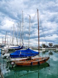 Sailboats moored at harbor against sky