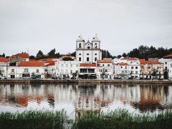 Buildings by river against sky in city