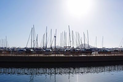 Sailboats in harbor against clear sky