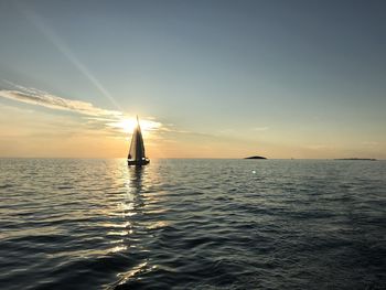 Sailboat sailing on sea against sky during sunset