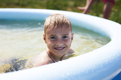 High angle portrait of happy boy in wading pool at yard