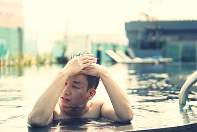 Shirtless man adjusting hair in swimming pool