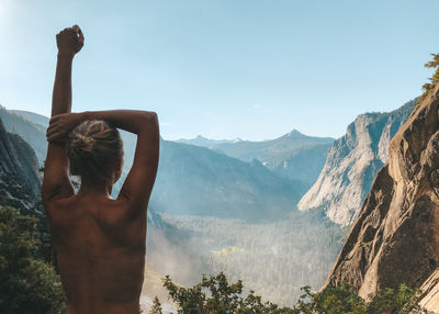 Rear view of shirtless woman standing on mountain