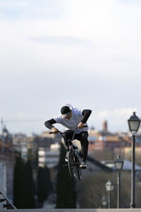 Man doing trick on bicycle in city at weekend