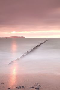 Wooden breakwater in wavy baltic sea. romantic atmosphere at smooth wavy sea. pink horizon 