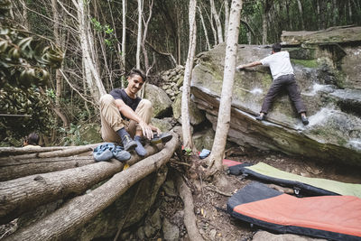 Pulled back view of a man climbing as another put shoes on