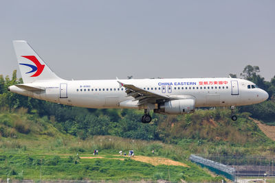 Airplane flying over field against sky