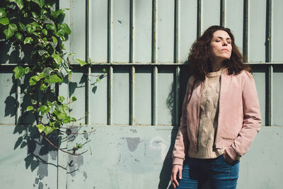 Portrait of beautiful young woman standing against wall