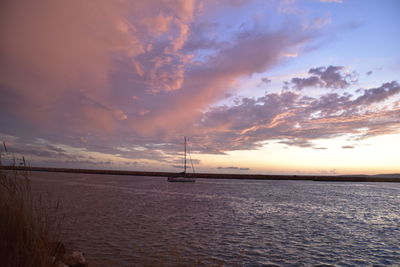 Sailboat sailing on sea against cloudy sky