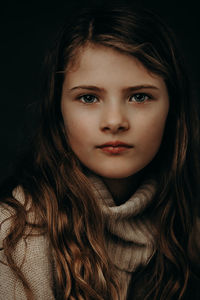 Close-up portrait of beautiful young woman over black background