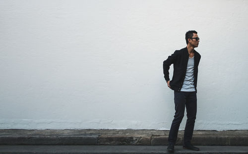 Young man standing against white wall