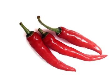 Close-up of red chili peppers over white background