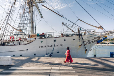 Rear view of woman walking on sailboat against sky