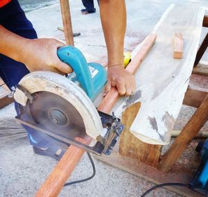 Midsection of man cutting wood