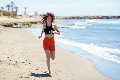 Full length of young woman standing at beach