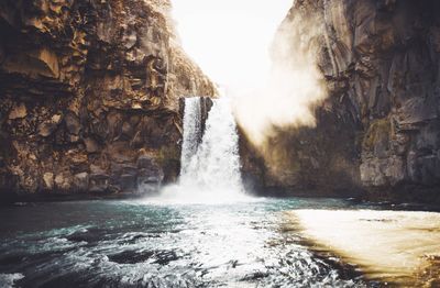 Water splashing on rocks against sky