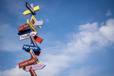 Low angle view of colorful road signs against sky