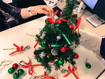 Cropped hands of business people decorating christmas tree at table in office